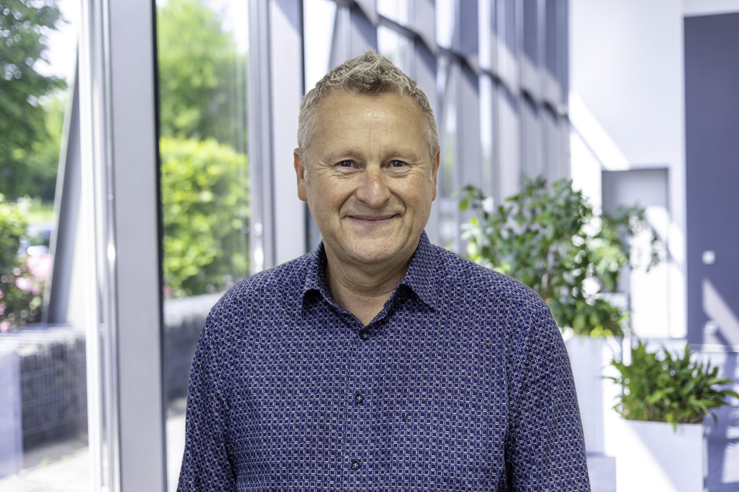 Joachim Kohn, specialist verbonden energieoplossingen, in de foyer voor een glazen gevel.
