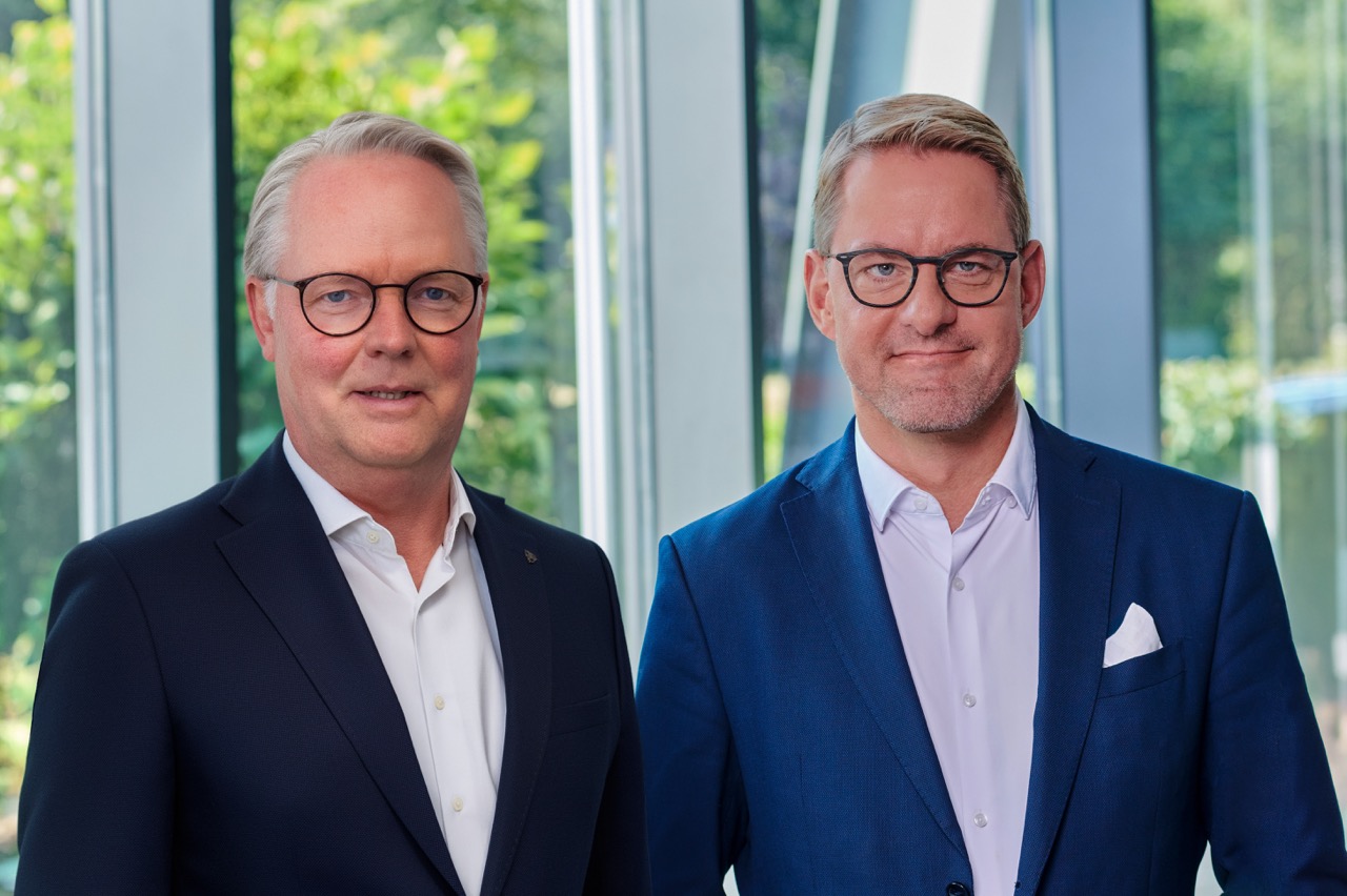 Van links: Jürgen Deters en Tobias Schulz (directie) in de lichte foyer, met grote ramen en planten op de achtergrond.