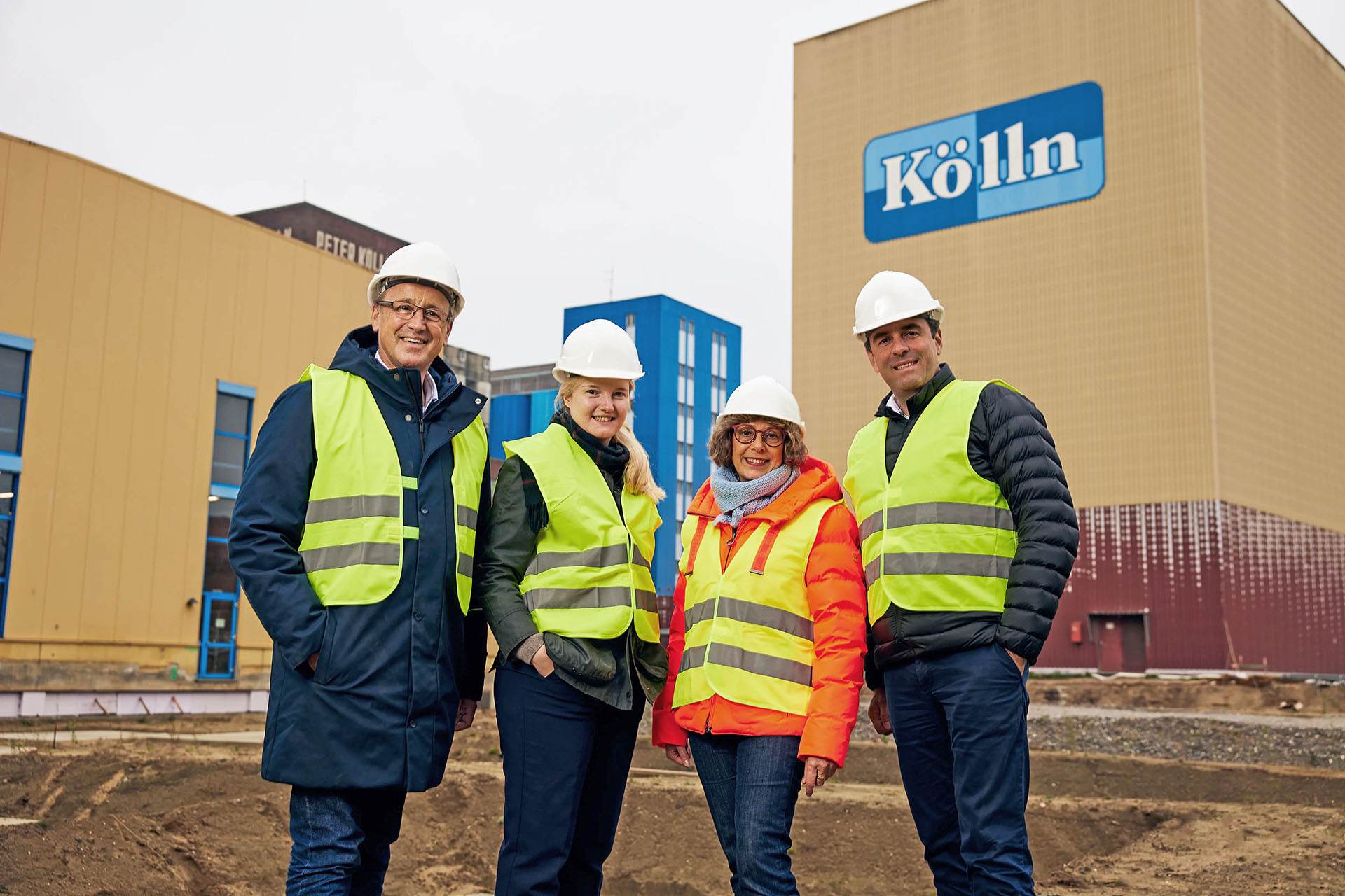 Vier personen met veiligheidshelmen voor de nieuwe productielocatie van Kölln.