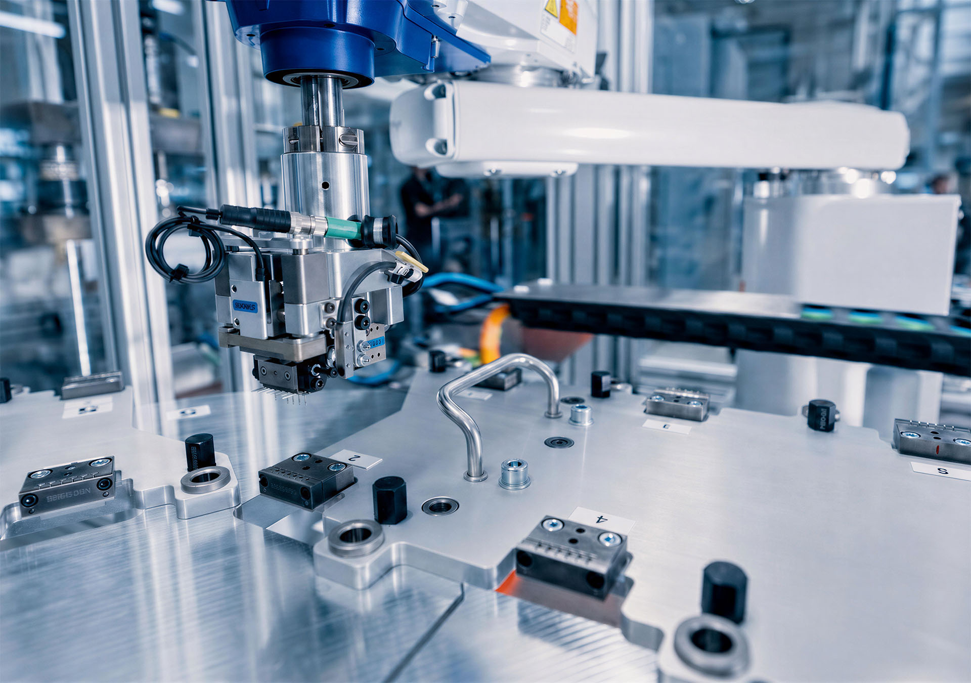 Grijpersysteem van een robot boven een opspanning in een geautomatiseerde productiecellen.